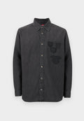 Schwarzes Denim-Hemd mit durchgehender Knopfleiste, langen Ärmeln, einem Kragen und drei bestickten Abzeichen auf der linken Brust. Strukturierter Stoff.