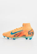 Leuchtend orangefarbener Fußballschuh mit strukturiertem Mesh-Obermaterial, blauen Akzenten, mittelhohem Schnitt und transparenter Sohle mit konischen Stollen.