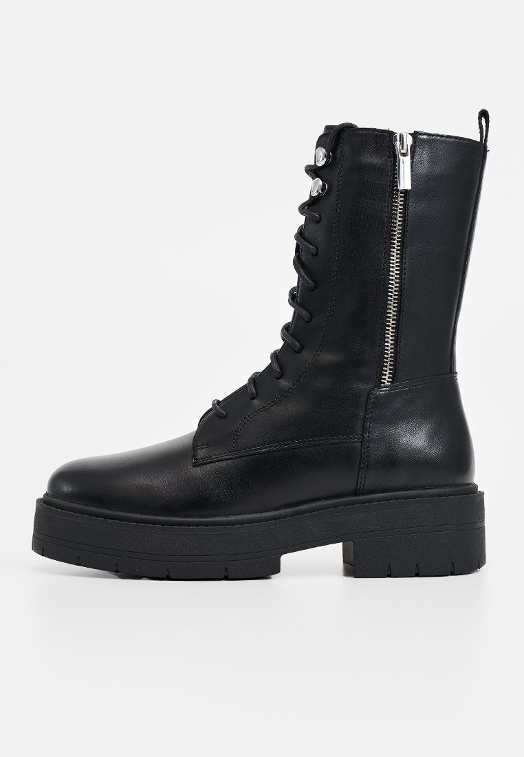 Schwarze Lederstiefelette mit schnürbarem Vorderteil, seitlichem Reißverschluss, klobigem Absatz und glatter Textur, die ein minimalistisches Design und eine robuste Verarbeitung aufweist.