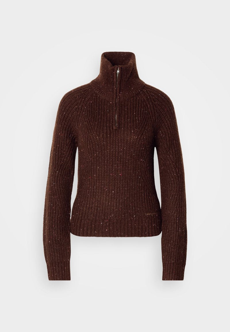 Brauner Strickpullover mit hohem Kragen und halbem Reißverschluss. Strukturiertes Muster mit roten und weißen Sprenkeln. Figurbetonte Silhouette.