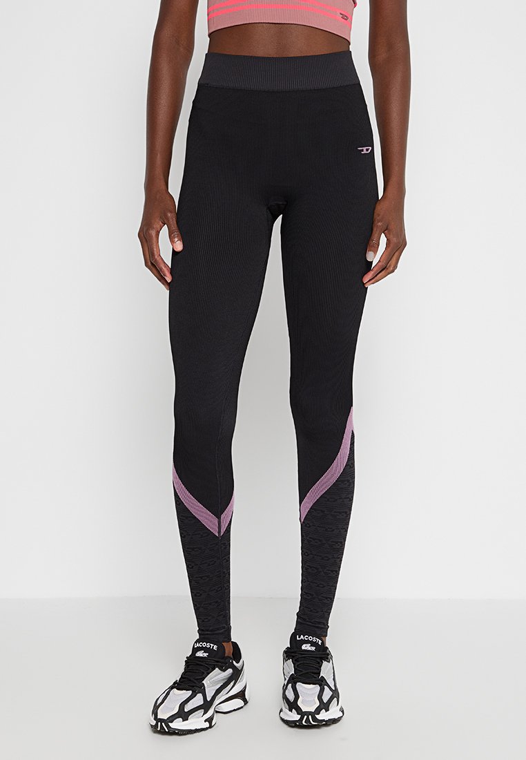 Schwarze, gerippte Leggings mit hoher Taille, die ein strukturiertes Detail in Grautönen und Violett entlang der Unterschenkel aufweisen. Kombinieren Sie sie mit Sneakers.