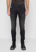 Schlanke schwarze Jeans, getragen von einer Person, die aufrecht steht, kombiniert mit schwarzen Sportschuhen, auf denen der Markenname sichtbar ist.