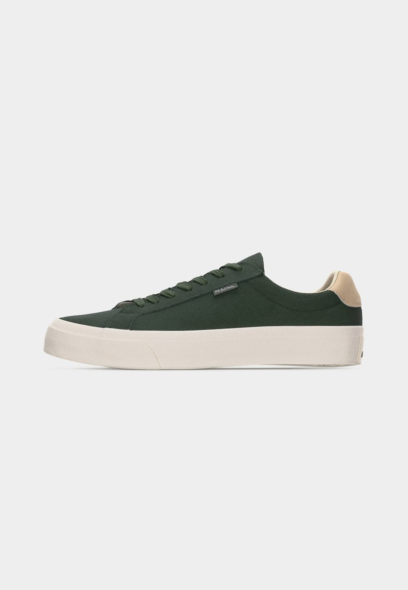 Dunkelgrüner Sneaker in niedriger Ausführung mit beigem Fersenlaschen, weißer dicker Sohle, Schnürung vorne und kleinem Seitentag auf hellem einfarbigem Hintergrund.