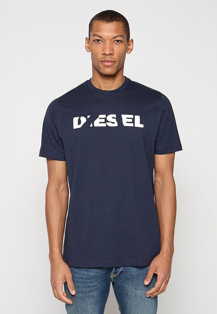 Marineblaues Baumwoll-T-Shirt mit rundem Ausschnitt und kurzen Ärmeln, das ein großes weißes "DIESEL"-Logo in Used-Optik über der Brust trägt.