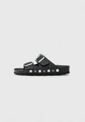 Schwarze Rutschsandalen mit zwei verstellbaren Riemen, silbernen Schnallen und metallischen Akzenten. Texturiertes Fußbett mit runden dekorativen Nieten.