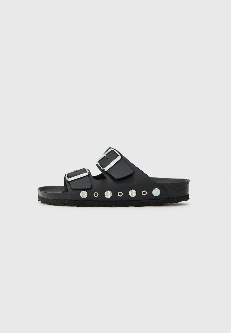 Schwarze Rutschsandalen mit zwei verstellbaren Riemen, silbernen Schnallen und metallischen Akzenten. Texturiertes Fußbett mit runden dekorativen Nieten.