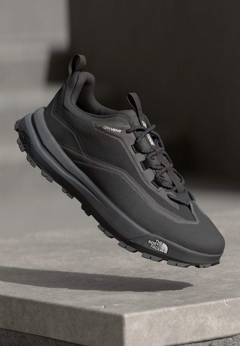 Schwarzer Trail-Laufschuh mit strukturiertem Obermaterial, Schnürsystem und dicker Gummisohle. Verfügt über "DRYVENT"-Markierung an der Seite.