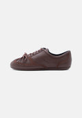 Brauner Sneaker mit niedrigem Schaft und Schnürsenkeln, mit gesteppter Wildleder-Details und "HUGO"-Logo an der Seite, seitlich auf weißem Hintergrund abgebildet.