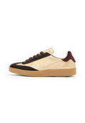 Goldene und schwarze Wildleder-Sneaker im Low-Top-Stil mit braunen Schnürsenkeln, texturiertem Gummisohle und Logodetail auf der Außenseite.