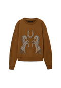 Das braune Sweatshirt verfügt über einen gerundeten Ausschnitt und überschnittene Schultern, mit einem Design aus zwei silbernen Pferden und einem Hufeisen auf der Vorderseite.