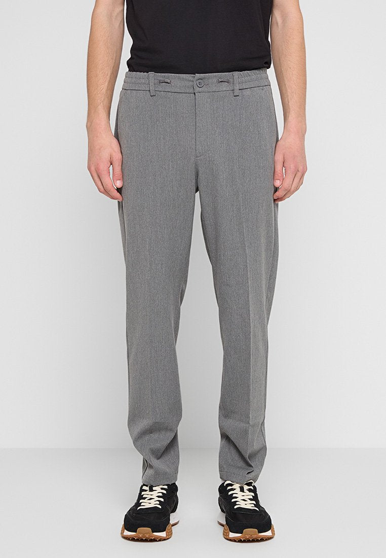 Grau maßgeschneiderte Hose mit geradem Schnitt, mit glatter Textur, Gürtelschlaufen und einem Knopfverschluss vorne, kombiniert mit schwarzen Sneakern.