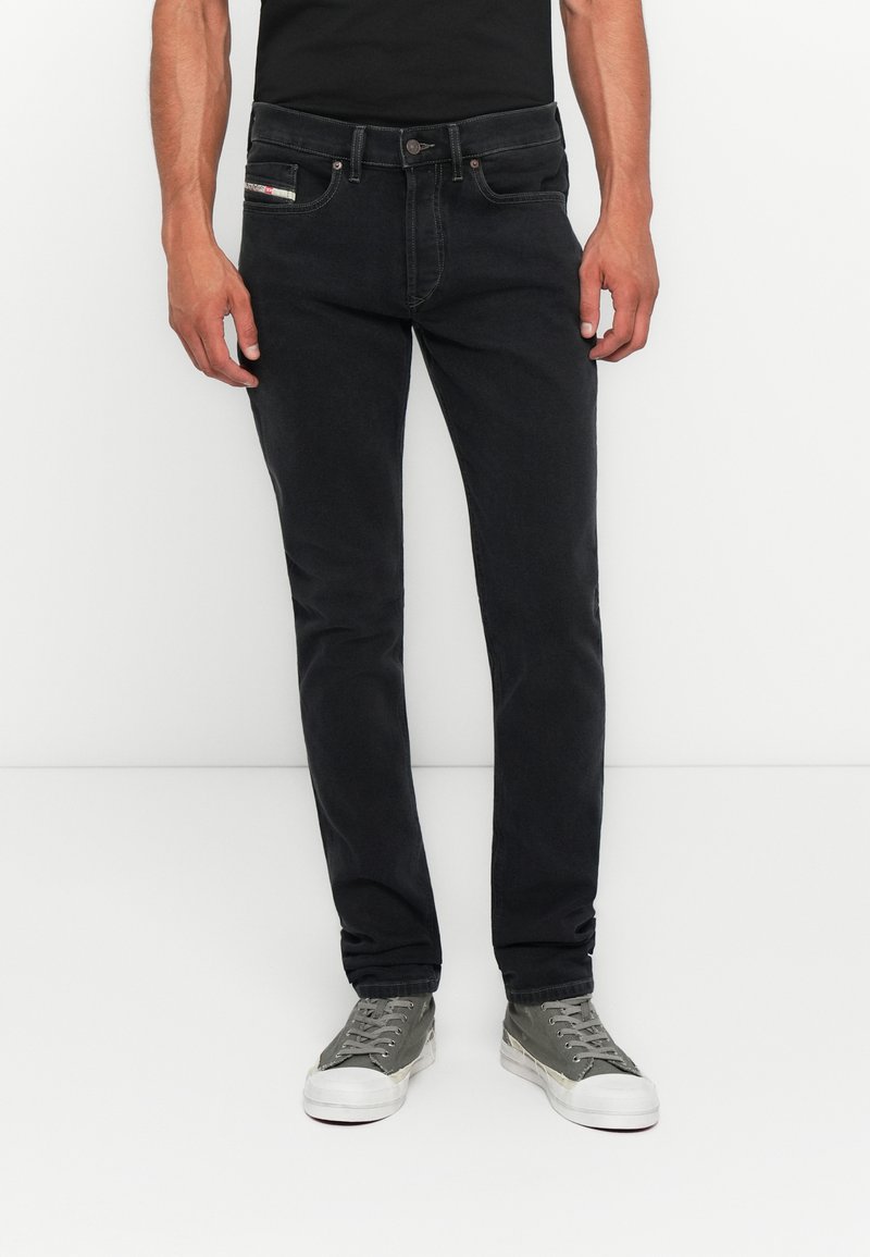 Schwarze Denim-Jeans im Slim-Fit, mit klassischem Fünf-Taschen-Design, Metallknopfverschluss und dezentem Branding auf der Vorderseite der Tasche.