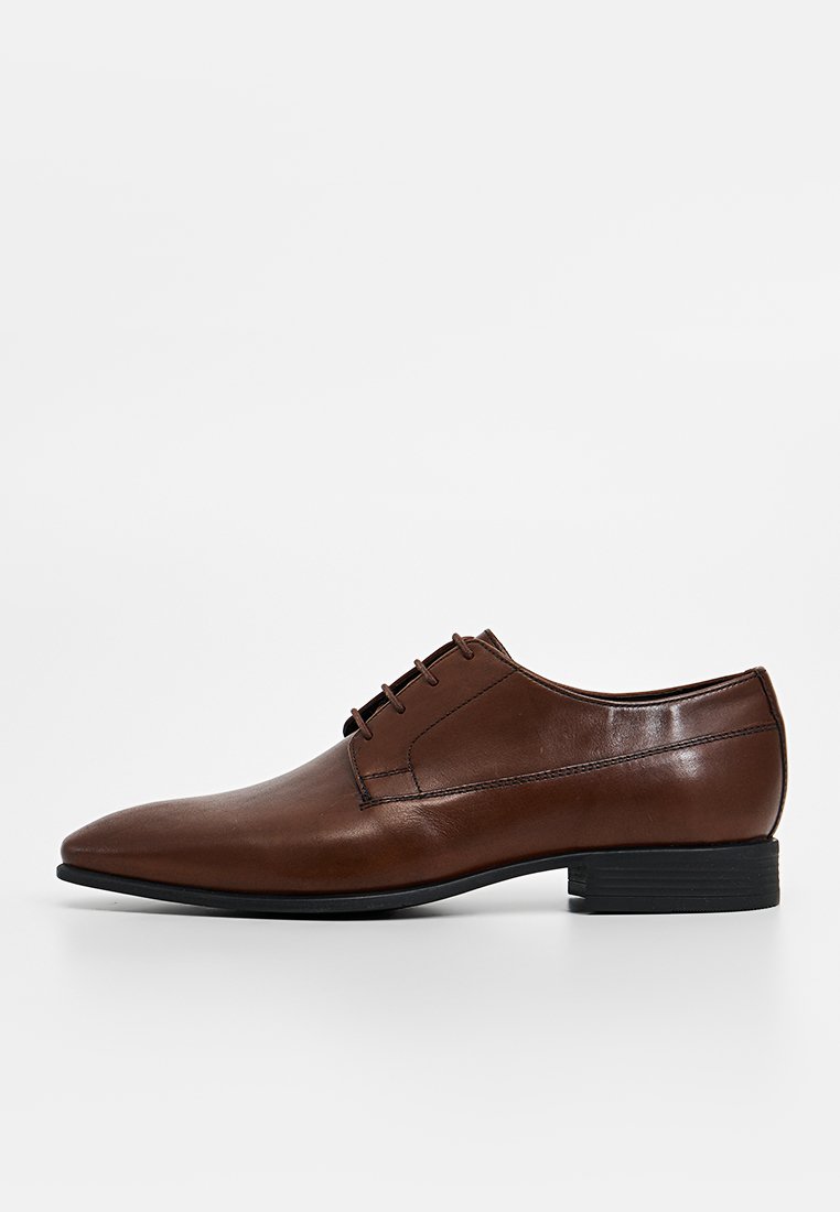 Braune Lederdressschuhe mit spitzer Zehenform, Schnürung auf der Vorderseite, glatter Textur und einem niedrigen schwarzen Gummihacken. Einfaches und elegantes Design.