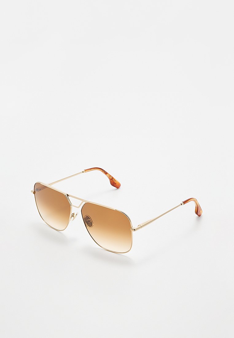 Elegante goldfarbene Aviator-Sonnenbrillen mit braunen Verlaufslinsen und Schildpatt-Tempelspitzen, die auf einer weißen Fläche liegen.