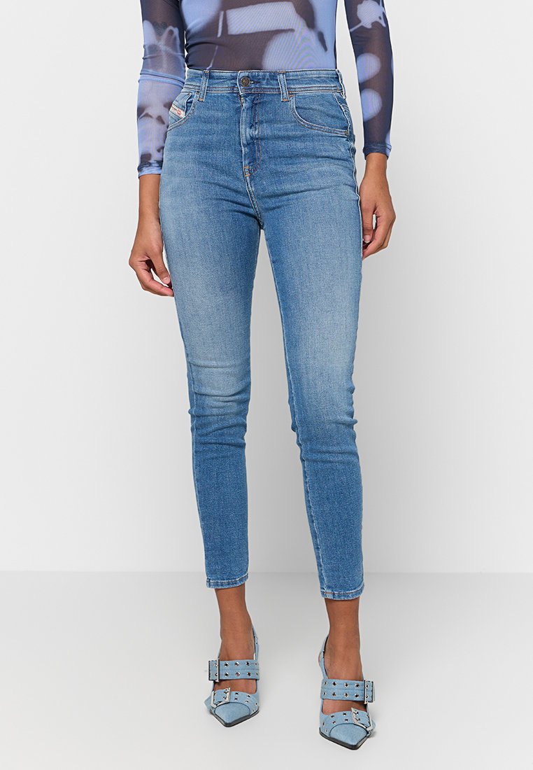 Hellblaue, enge Jeans mit hoher Taille, fünf Taschen und dezenten Verblassungen. Kombiniert mit hellblauen, mit Nieten versehenen Absätzen.