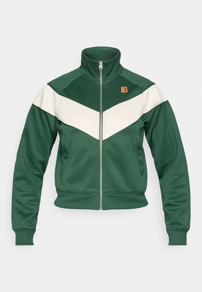 Grüne Trainingsjacke mit hohem Kragen, weißem Chevron-Design, Reißverschluss und gerippten Bündchen. Mit einem Logopatch auf der Brust.