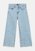 Hellblaue Jeans mit weitem Bein, verziert mit kleinen weißen Gänseblümchen-Stickereien und rohen Saumkanten.