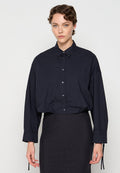 Dunkelblaues Button-Up-Shirt mit spitzem Kragen, langen, lockeren Ärmeln, einer Brusttasche und gerafften Details an den Manschetten.