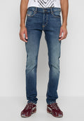 Blaue Denim-Jeans mit schmaler Passform, leichter Ausbleichung an den Beinen, fünf Taschen und kontrastierenden Nähten, kombiniert mit burgunderroten Sportschuhen.