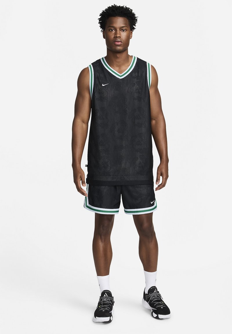 Schwarzes Basketballtrikot mit einem strukturierten Muster, ausgestattet mit einem grünen und weißen Saum, kombiniert mit passenden Shorts, alles von Nike.