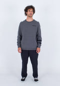 Grauer Sweatshirt mit rundem Halsausschnitt und Schulterpaneelen. Schwarzes Logo auf der Brust. Kombiniert mit dunklen Hosen und schwarzen Sneakers.