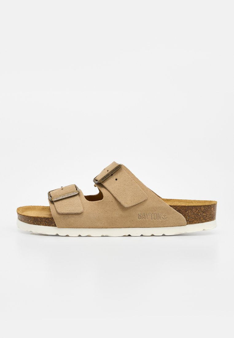 Beige Wildleder-Slide-Sandale mit zwei verstellbaren Riemen, Kork-Fußbett, weißer Sohle und seitlich geprägt mit dem "BAYTON" Logo.