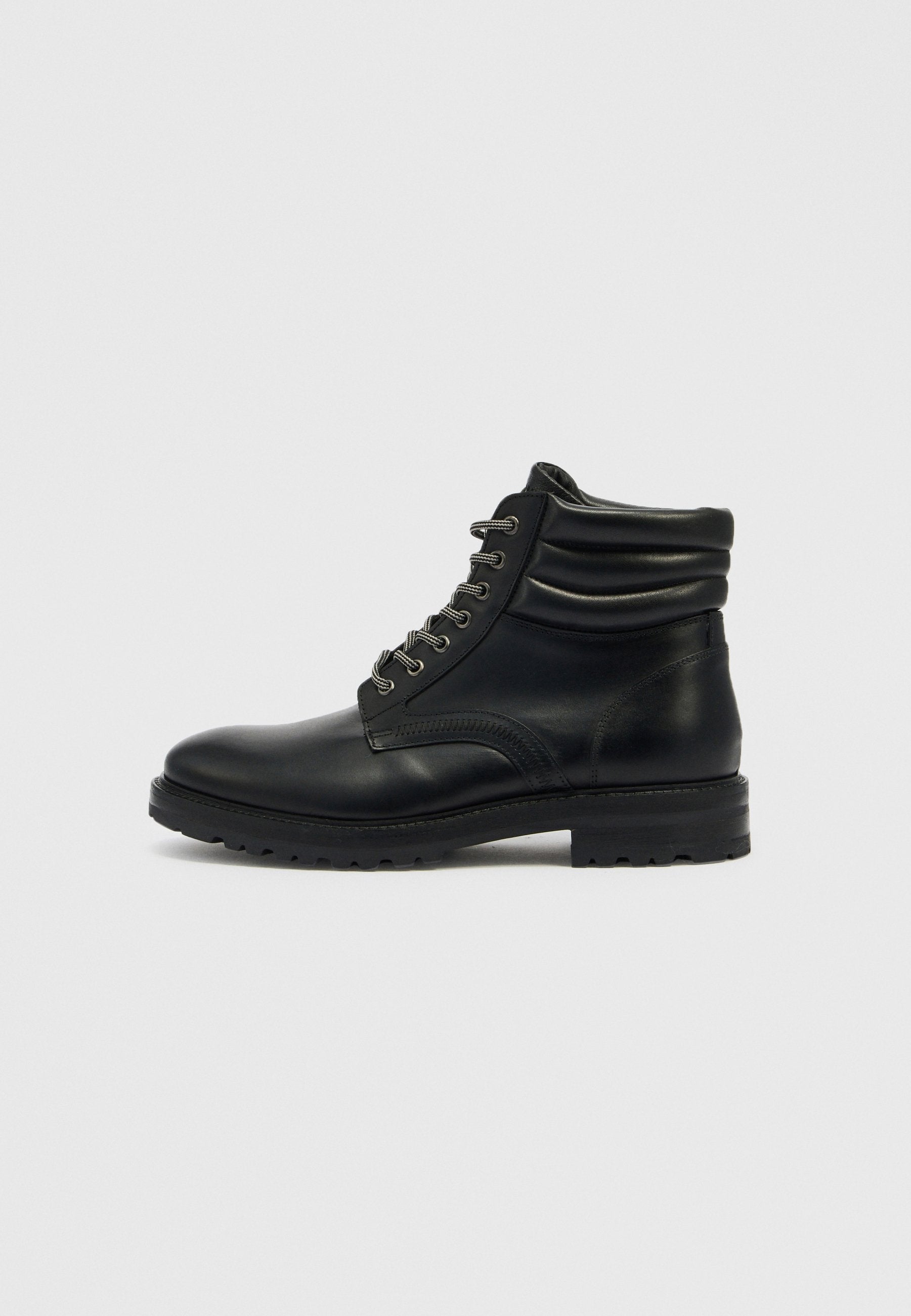 Schwarze Leder-Stiefeletten mit runder Spitze, Schnürdesign, lockerem Schaft und strukturierter Sohle. Mit silberner Hardware und Nahtdetails.