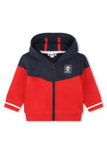 Rot- und marineblaue Kapuzenjacke mit Reißverschluss aus weichem Stoff, ausgestattet mit einer Kapuze, weißen Akzentstreifen an den Ärmeln und dem Timberland-Logo auf der Brust.