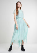 Helles mintgrünes Chiffonkleid mit kurzen Ärmeln, gerafft an der Taille, fließendem Saum und transparenter Überlage. Getragen mit schwarzen Knöchelstiefeln.