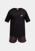 Schwarzes T-Shirt mit kurzen Ärmeln, einem Kirschmotiv und einem roten Diesel-Label. Kombiniert mit gemusterten Shorts, die rote Kirschen auf einem dunklen Hintergrund zeigen.