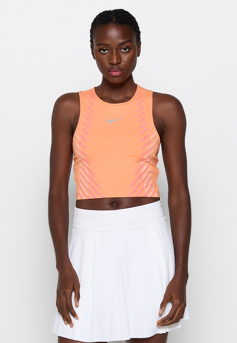 Nike-Crop-Top in Hellorange mit pinken diagonalen Streifen, aus dehnbarem Material gefertigt. Hat einen runden Ausschnitt und ein figurbetontes Design.