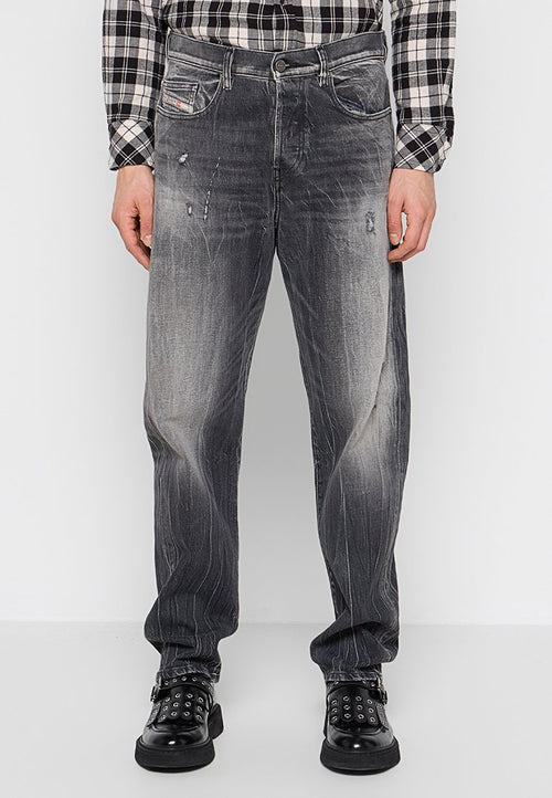 Ausgewaschene schwarze Jeans mit lockerem Schnitt, ausgestattet mit abgetragenen Details, fünf Taschen und einem Knopfverschluss. Tragen Sie dazu schwarze Schuhe.