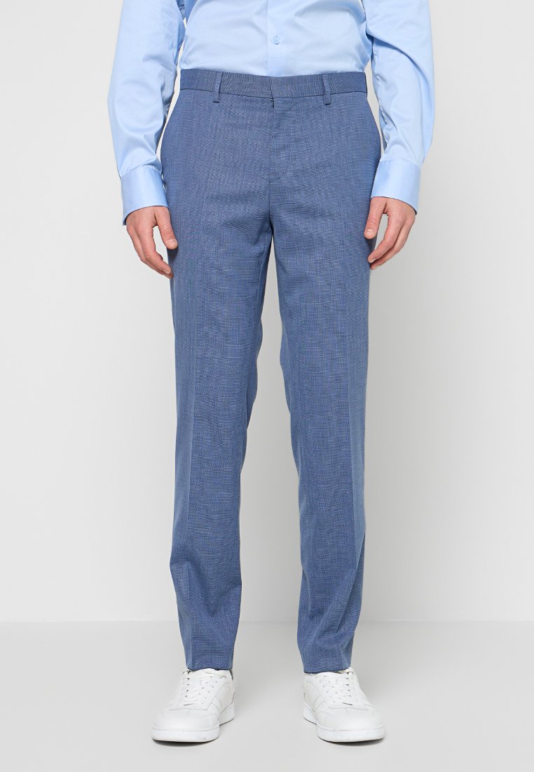 Hellblaue strukturierte Hose mit schmaler Passform, flacher Vorderseite und Gürtelschlaufen, kombiniert mit weißen Turnschuhen und einem hellblauen Langarmhemd.