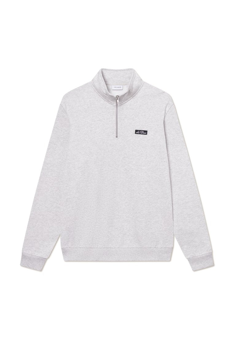 Hellgrauer Sweatshirt mit hohem Kragen und Viertelreißverschluss. Mit gerippten Bündchen und Saum, sowie einem kleinen schwarzen Logopatch auf der Brust.