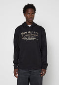 Junger Mann, der einen schwarzen O'Neill California Santa Cruz Hoodie und dunkle Jeans trägt, vor einem schlichten hellen Hintergrund steht.