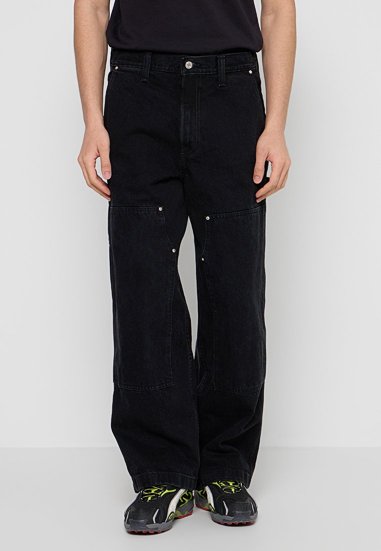 Schwarze weite Jeans aus Denim, mit hoher Taille, großen Vorderaschen und metallischen Knopfdetails.