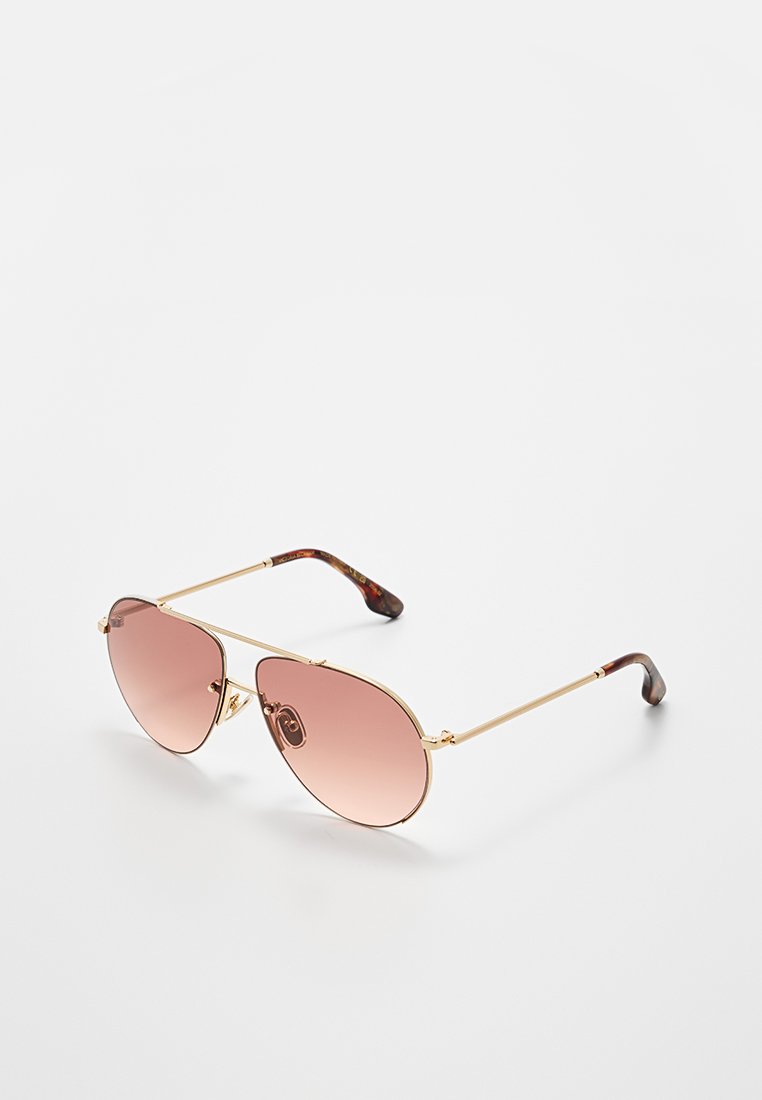 Pilotensonnenbrille mit goldenen Metallrahmen, verlaufenden rosa Gläsern und einem Grauflecht-Muster an den Bügelspitzen. Leicht und schlank im Design.