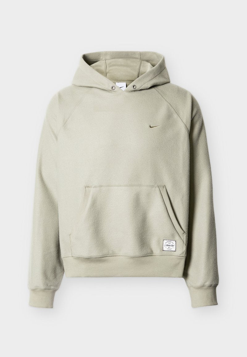 Hellbeige Kapuzen-Fleecejacke mit Fronttasche, kleinem Nike-Swoosh auf der Brust und rechteckigem weißem Stoffetikett nahe der Taille.