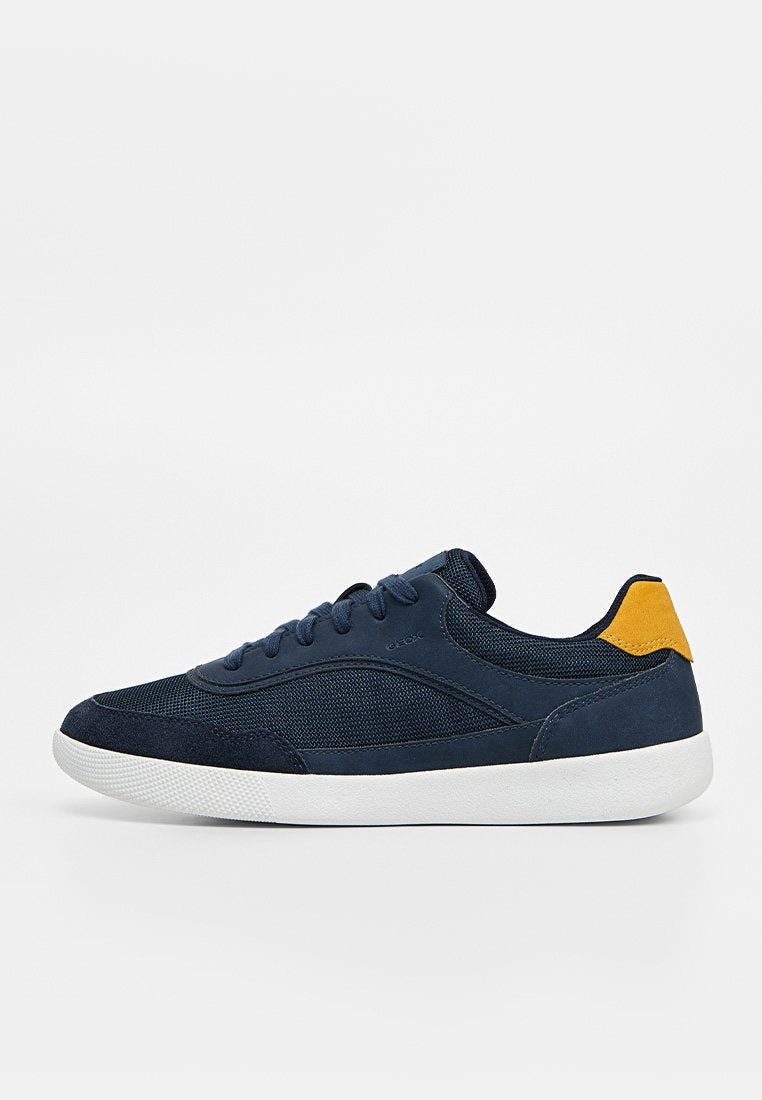 Navyblauer Sneaker mit Mesh- und Wildledereinsätzen, weißer Sohle, gelber Fersenlasche und navyblauen Schnürsenkeln, in rechter Seitenansicht gezeigt.