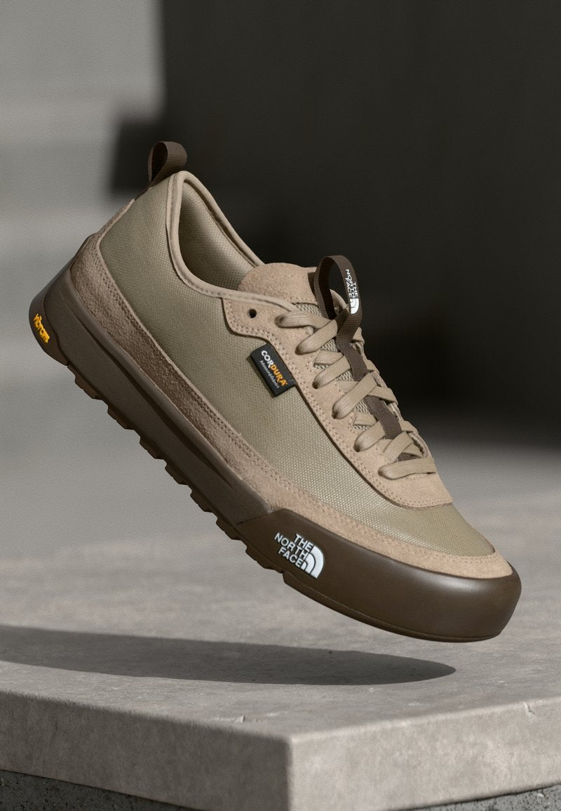 Beige Sportschuh mit Obermaterial aus Mesh und Wildleder, brauner Gummisohle, gepolstert, mit Logoakzenten und Schnürdesign.