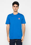 Blaues Baumwoll-T-Shirt mit Rundhalsausschnitt, kurzen Ärmeln und einem kleinen rot-weißen Logopatch auf der linken Brust. Glatte Textur, legere Passform.