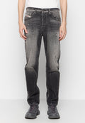 Schwarze Denim-Jeans mit einem distressed Finish, verblasster Textur, zwei vorderen Taschen und einem Knopfverschluss. Kombiniert mit grauen Sportschuhen.