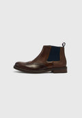 Brauner Chelsea-Stiefel aus Leder mit navyblauen elastischen Seitenteilen, perforierten Details und einer Lasche an der Ferse. Abgerundete Spitze und niedriger Absatz.