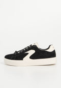 Schwarze Wildleder-Sneaker mit cremefarbenen Akzenten, runder Zehenform, Schnürdesign und einer dicken weißen Gummisohle. Niedriges Profil mit Logodetails.