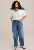 Weißes Hemd mit kurzen Puffärmeln, kombiniert mit hochtaillierten blauen geraden Jeans. Getragen mit weißen und grauen Sneakers.