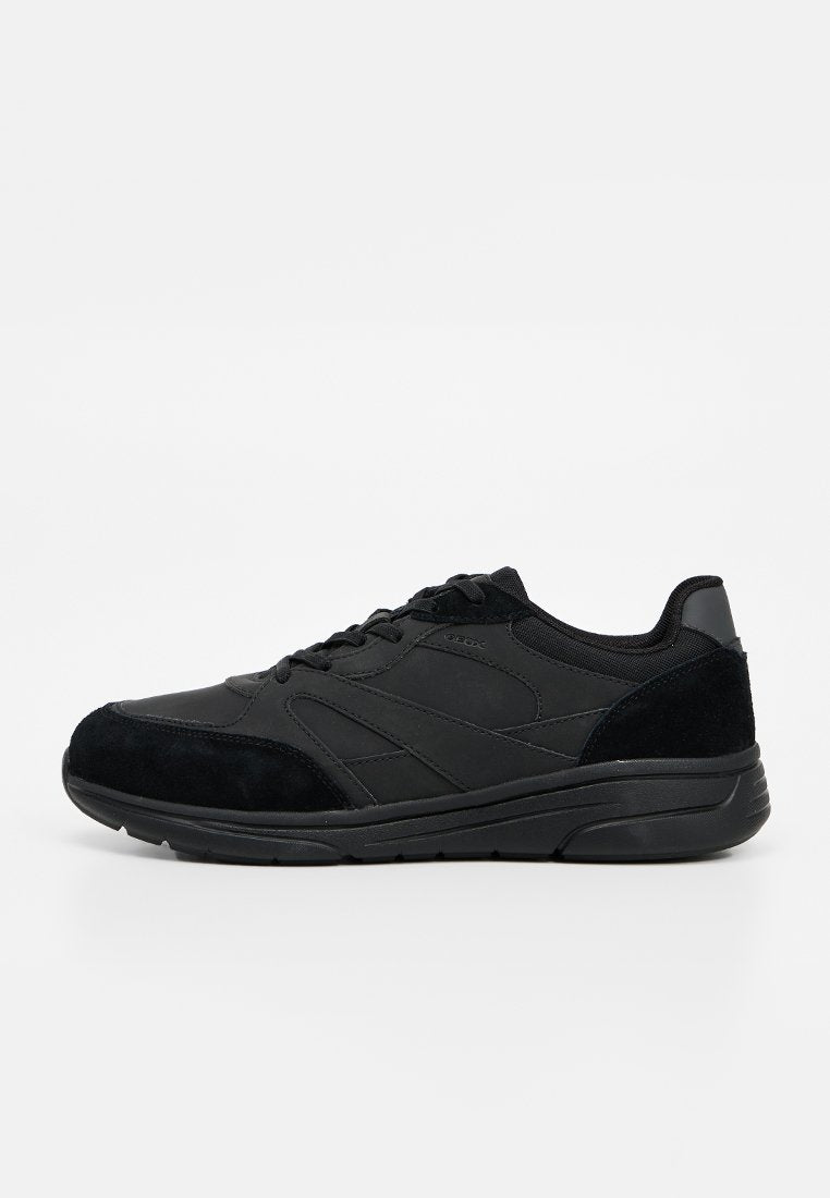 Schwarzer Schnürsneaker mit Wildleder- und synthetischen Einsätzen, gepolsterter Sohle und gepolstertem Kragen, seitlich auf weißem Hintergrund gezeigt.