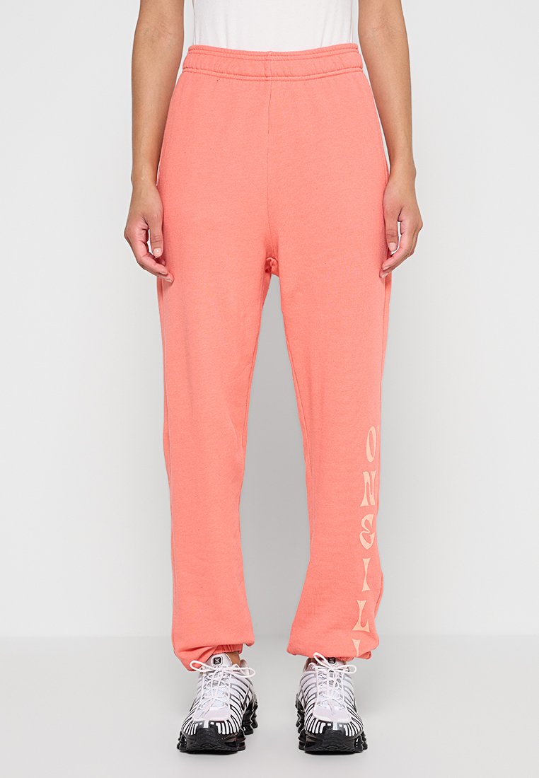 Korallefarbene Sweatpants aus weichem Stoff, mit einem elastischen Bund und schmal zulaufenden Beinen. "Only" in einer stilisierten Schriftart auf dem linken Bein gedruckt.