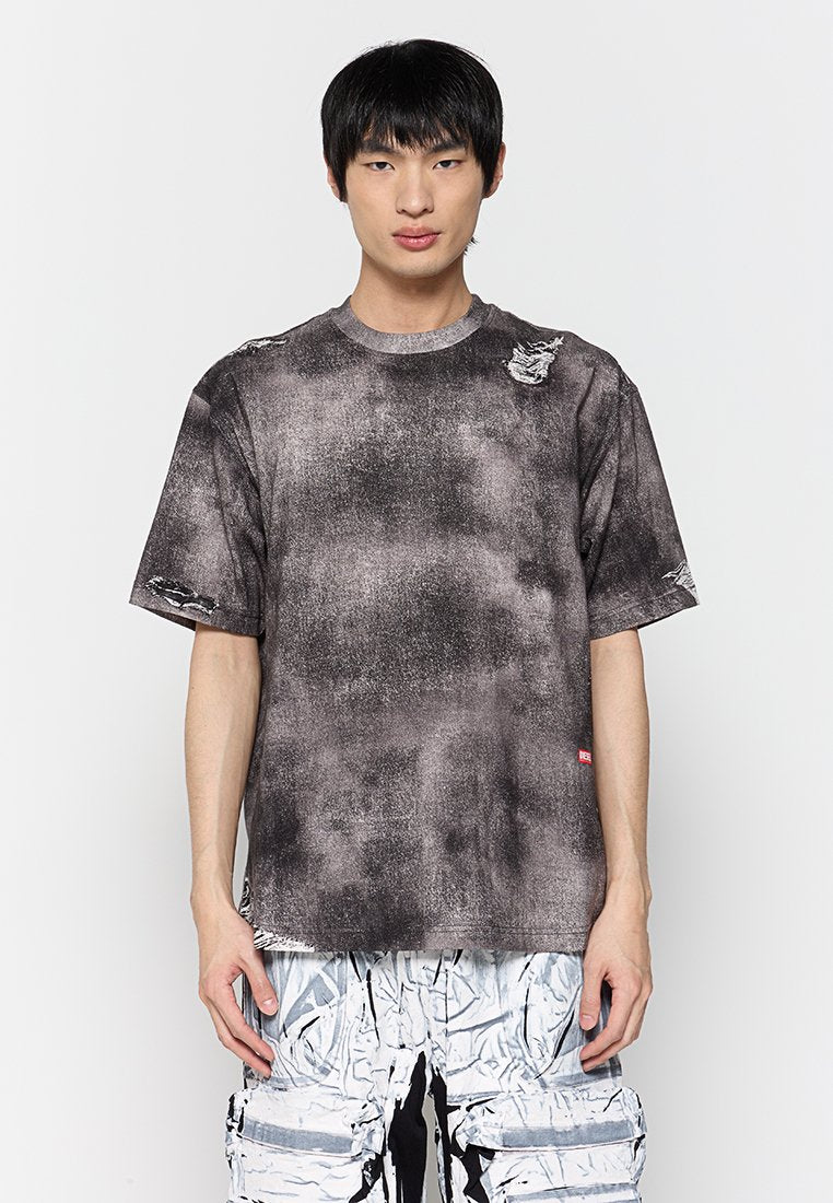 Übergroßes graues T-Shirt mit einem verbrannten Finish, das ausgefranste Kanten und ein kleines Logoschild aufweist. Getragen mit weißen karierten Cargo-Hosen.