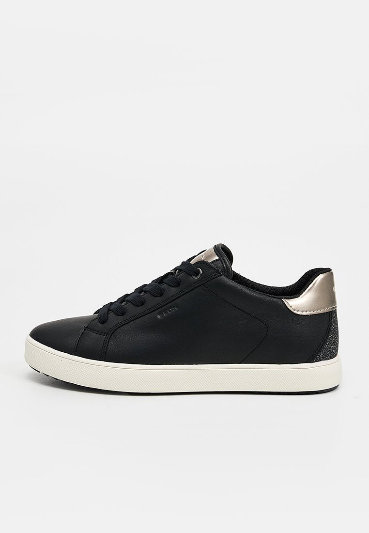 Schwarzer Low-Top-Sneaker mit weißer Sohle, schwarzen Schnürsenkeln und metallischem silbernen Fersendetail vor schlicht weißem Hintergrund.