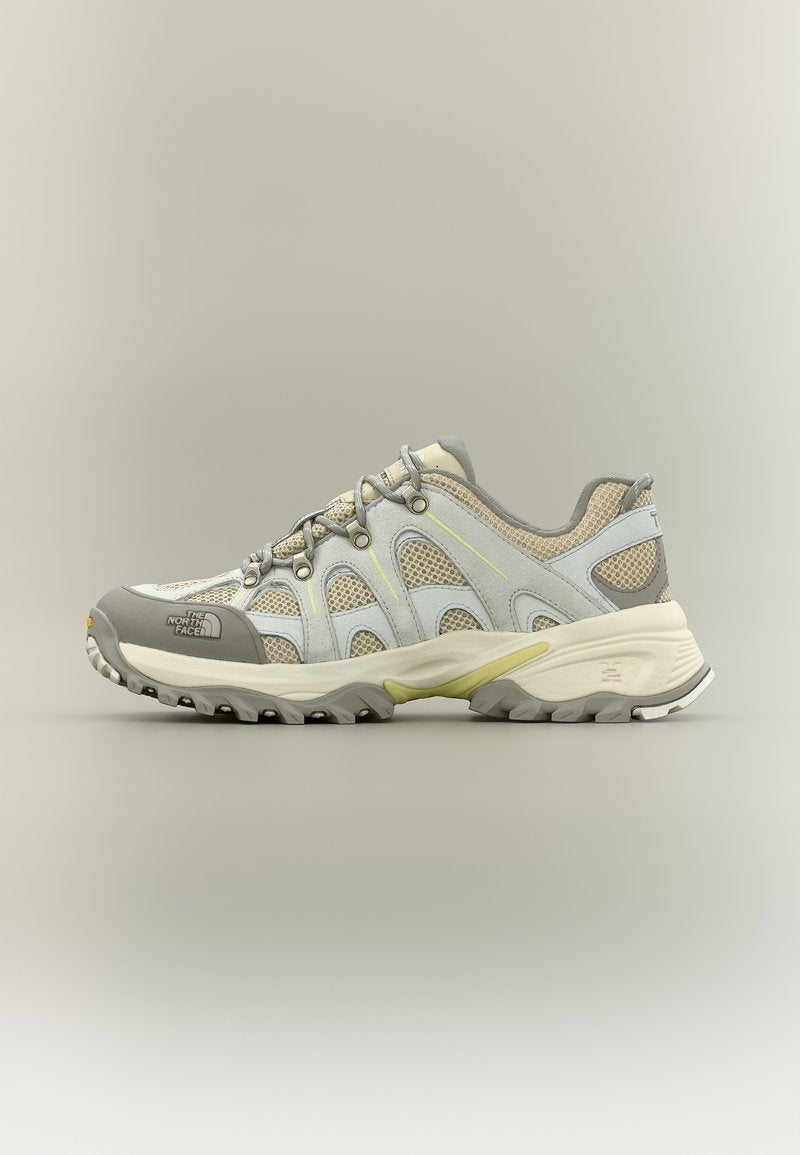 Hellgrauer und beigefarbener Trailrunning-Schuh mit Mesh-Einsätzen, strapazierfähiger Sohle und Schnürdesign, mit dem The North Face Logo auf der Zehenkappe.